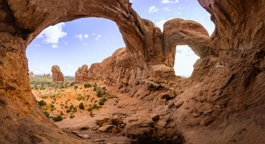 Delicate Arch at Arches National Park in Utah with red rock formations under a bright blue sky.